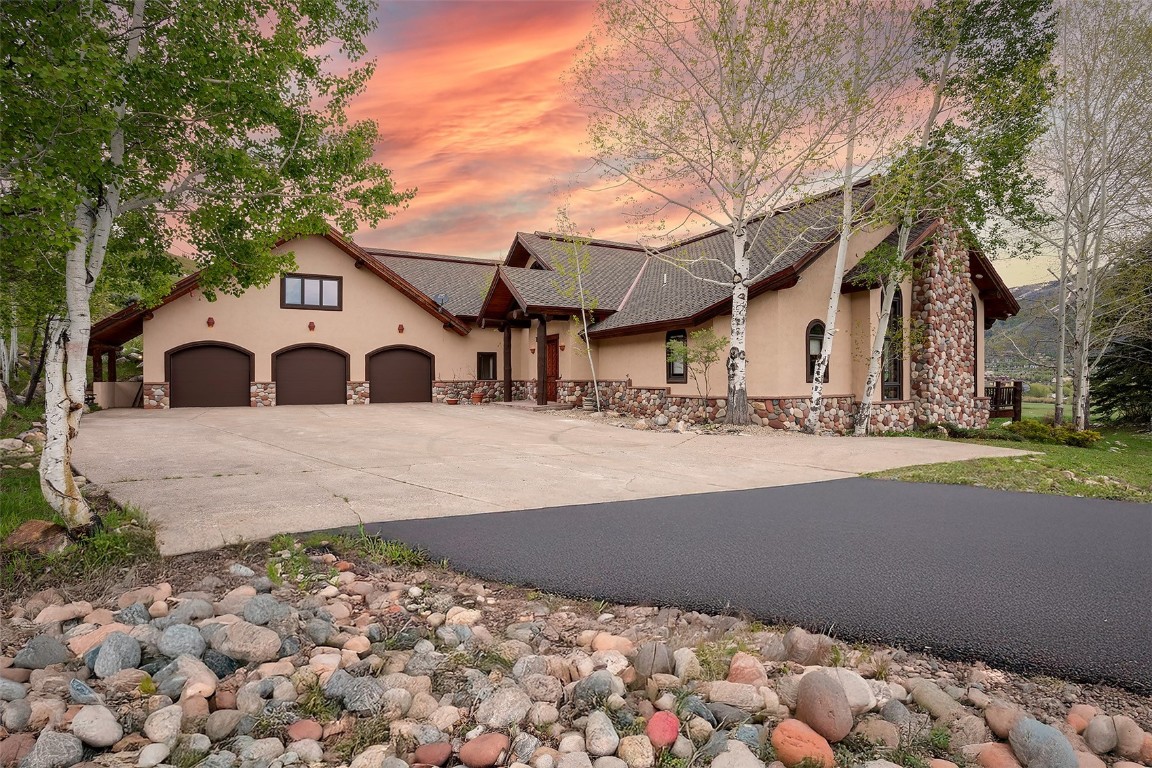 View of front facade with stucco siding, concrete driveway, an attached 3 car garage, and stone siding