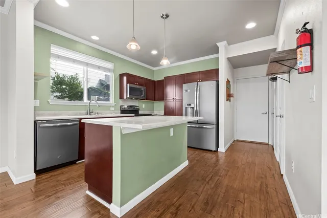 a kitchen with stainless steel appliances granite countertop a refrigerator a sink dishwasher a stove and a dining table with wooden floor