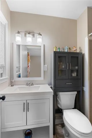 a bathroom with a toilet sink vanity and mirror