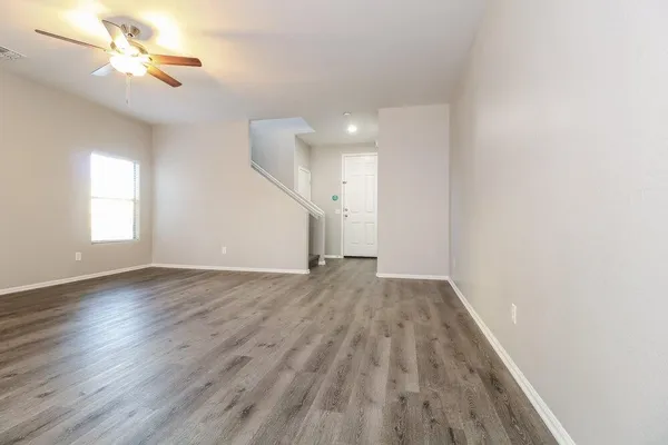 an empty room with wooden floor chandelier fan and windows