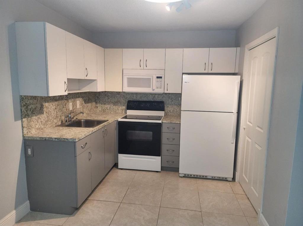 8709 Northwest 57th Drive Tamarac, FL 33321 - Photo 28 of 34 a kitchen with a refrigerator sink stove and cabinets