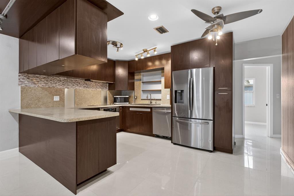 8709 Northwest 57th Drive Tamarac, FL 33321 - Photo 3 of 34 a kitchen with kitchen island a counter top space stainless steel appliances and cabinets
