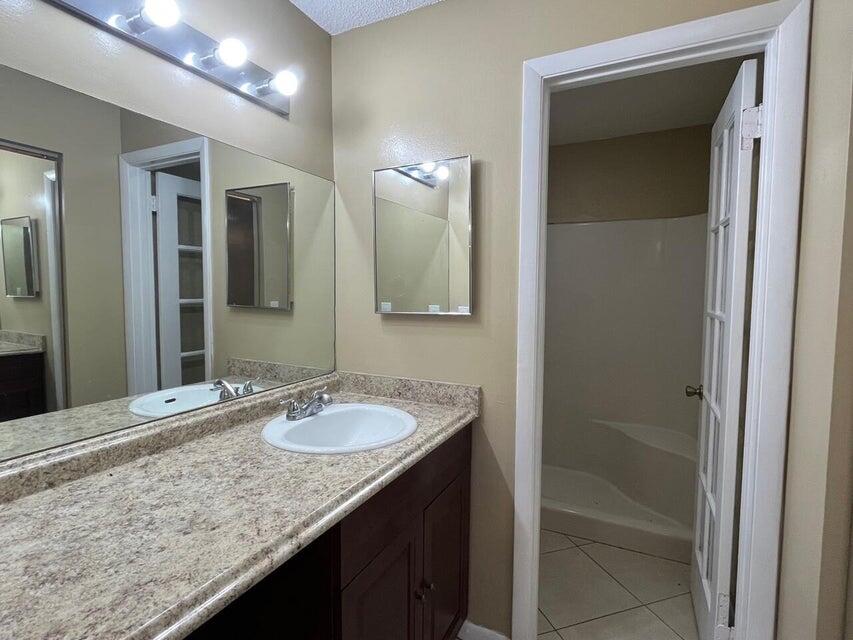 5249 Tennis Lane Delray Beach, FL 33484 - Photo 9 of 23 a bathroom with a granite countertop sink and a mirror