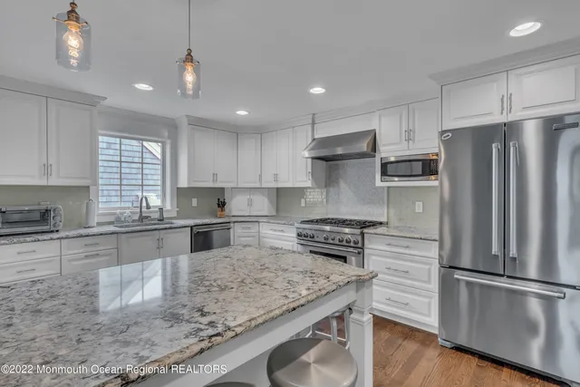 a kitchen with stainless steel appliances granite countertop a refrigerator a sink a stove a microwave and island