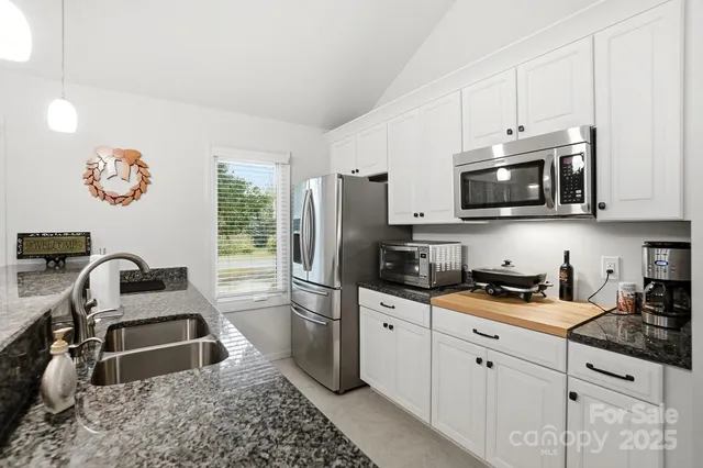 a kitchen with stainless steel appliances granite countertop a sink and chairs