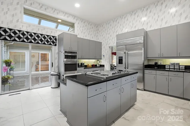 a kitchen with stainless steel appliances granite countertop a table chairs sink and cabinets