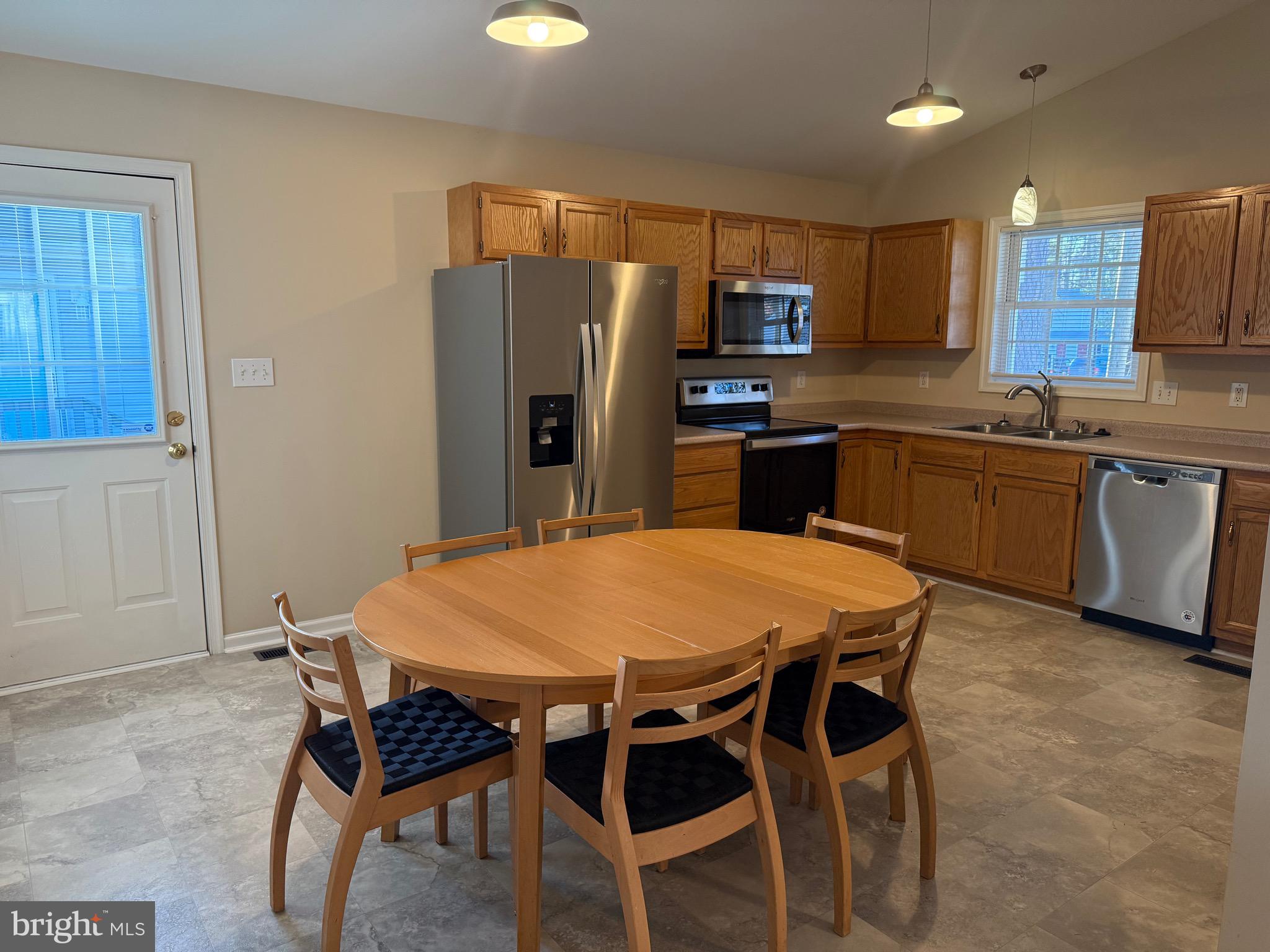 328 12th Street Colonial Beach, VA 22443 - Photo 5 of 19 a kitchen with stainless steel appliances granite countertop a sink a stove a refrigerator cabinets a dining table and chairs