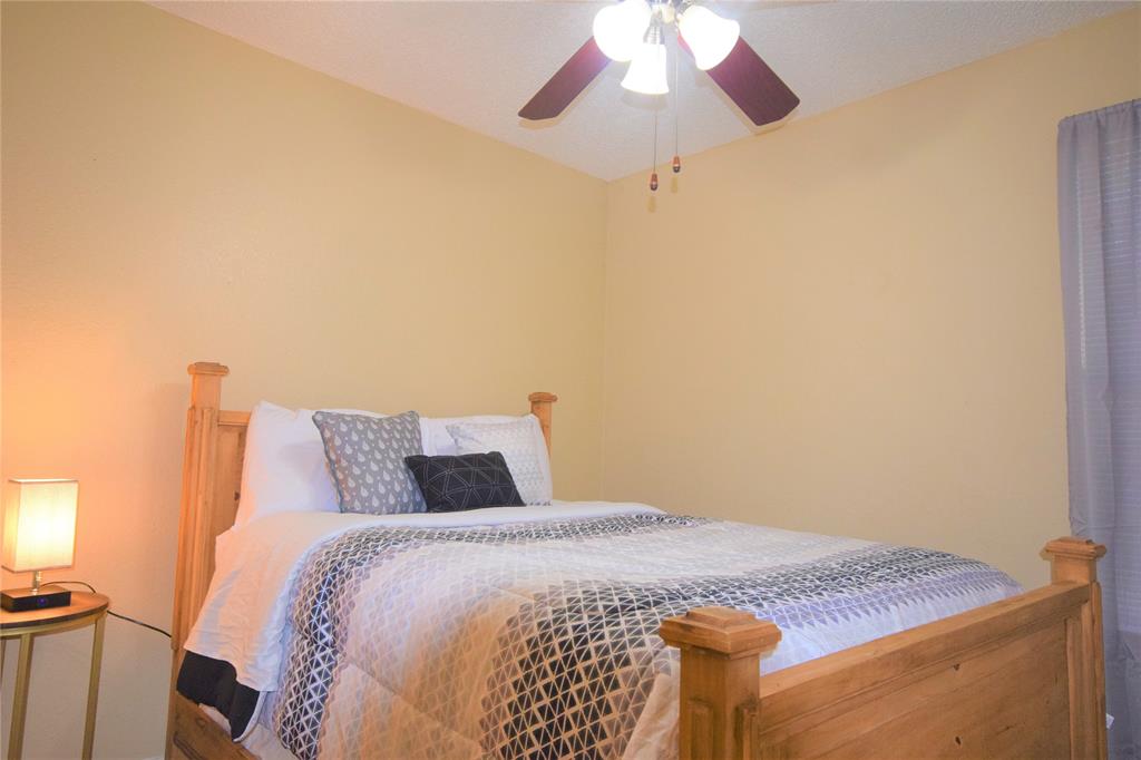 4909 Jamesway Road, Unit 203D Fort Worth, TX 76135 - Photo 16 of 17 a bedroom with a bed and a chandelier