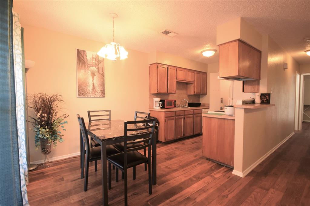 4909 Jamesway Road, Unit 203D Fort Worth, TX 76135 - Photo 7 of 17 a kitchen with a table chairs refrigerator and microwave