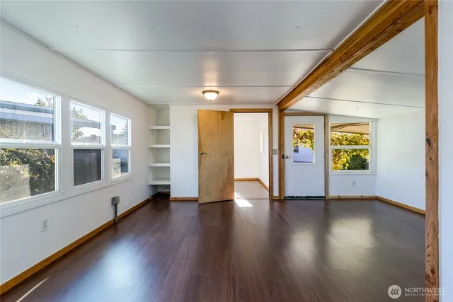 a view of an empty room with wooden floor and a window