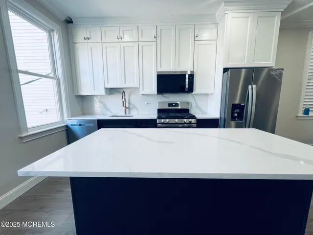a kitchen with stainless steel appliances a refrigerator sink and white cabinets