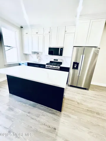 a large white kitchen with wooden floor