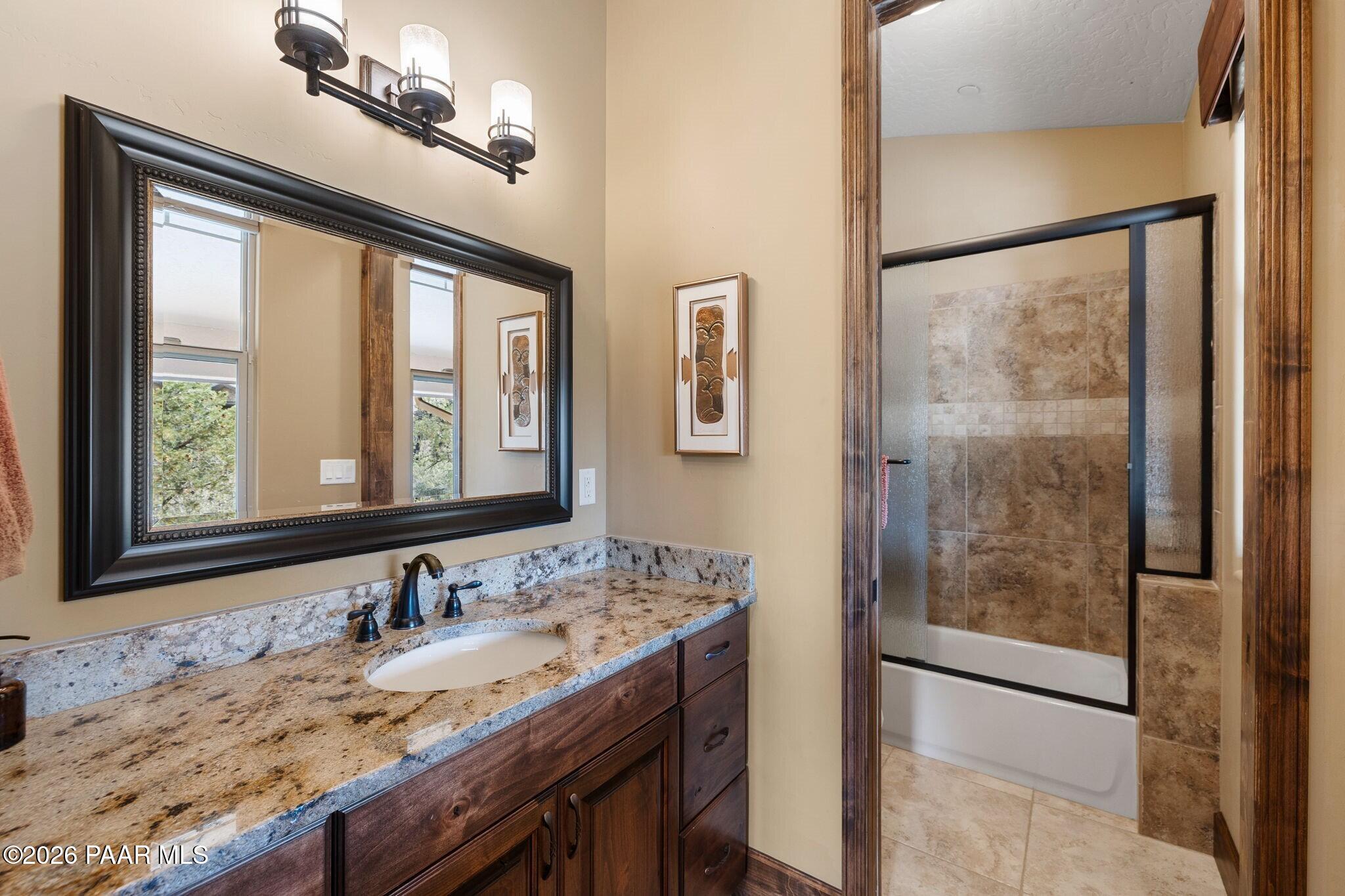 4290 Fort Bridger Road Prescott, AZ 86305 - Photo 26 of 50 a bathroom with a granite countertop sink a mirror and shower