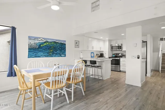 a kitchen with stainless steel appliances a sink a stove a refrigerator cabinets and chairs