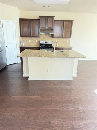 a large white kitchen with kitchen island a sink a stove a oven and white cabinets