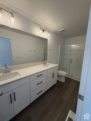 2019 Leap Frog Road, Unit 916 Eagle Mountain, UT 84005 - Photo 8 of 15 Double vanity with white cabinetry, wood-finish flooring, glass-enclosed shower, and modern lighting fixtures