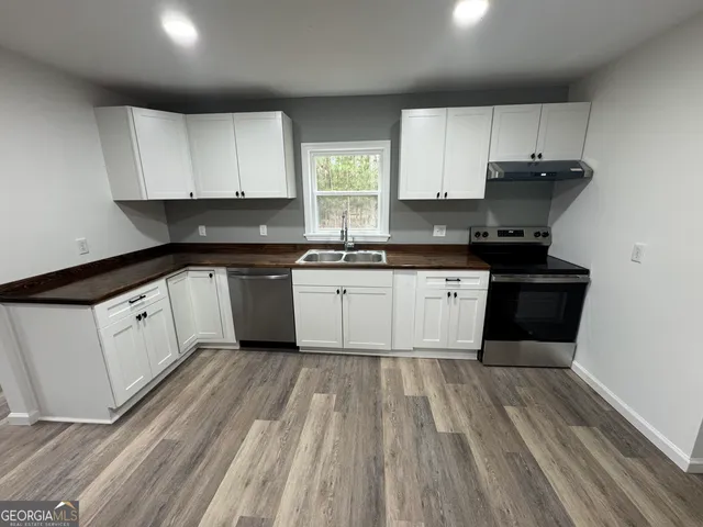 a kitchen with granite countertop a sink cabinets and stainless steel appliances