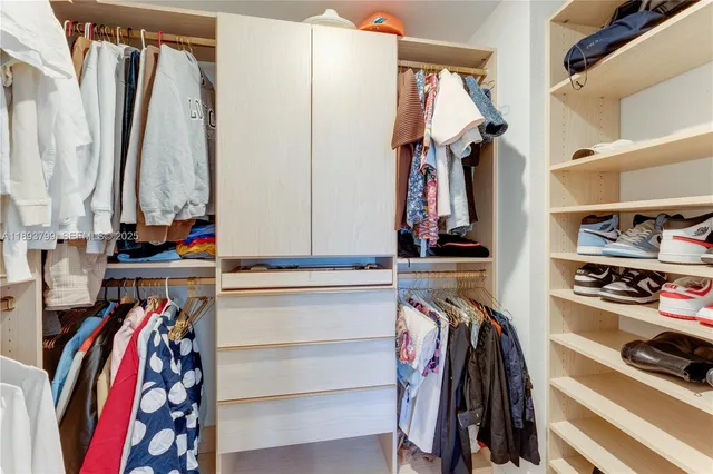 a view of walk in closet with clothes and shoes