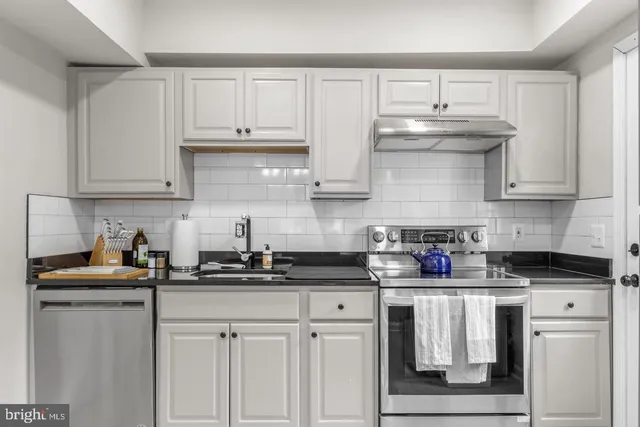 a kitchen with white cabinets and appliances