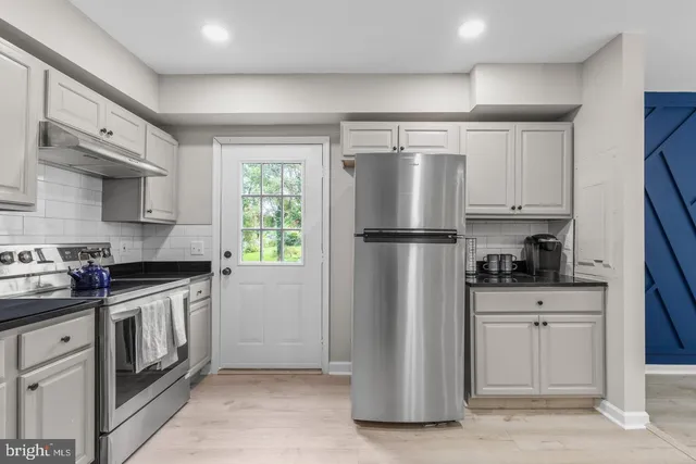 a kitchen with granite countertop a refrigerator stove and sink