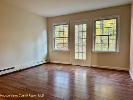 an empty room with wooden floor and windows