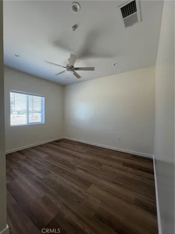 an empty room with wooden floor fan and windows