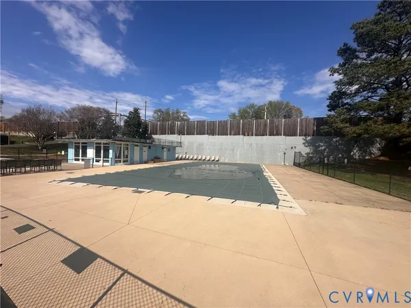 a view of swimming pool with large trees and buildings in the background