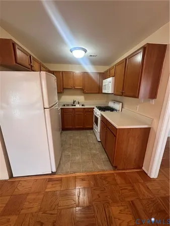 a kitchen with granite countertop a refrigerator a sink a stove a microwave a counter top and cabinets