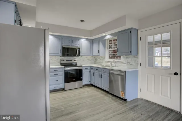 a kitchen with stainless steel appliances granite countertop a stove top oven a sink dishwasher a refrigerator and a microwave oven with wooden floor