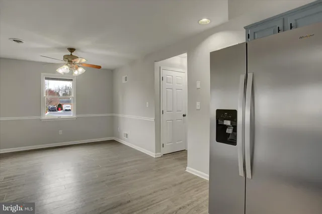 an empty room with wooden floor and a ceiling fan