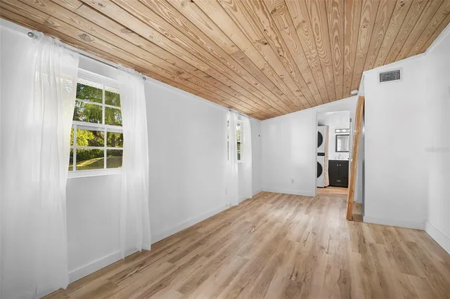 a view of a hallway with wooden floor and a kitchen