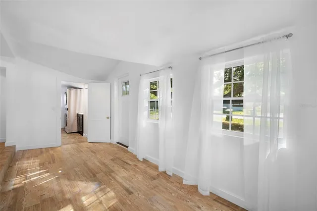 a view of a bedroom with wooden floor and windows