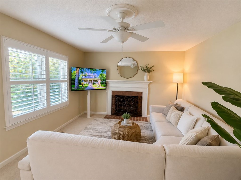 2018 Cardinal Park Drive Anderson, SC 29621 - Photo 2 of 11 A well-lit living space features a cozy fireplace, framed by plantation shutters on a wide window, and a ceiling fan.