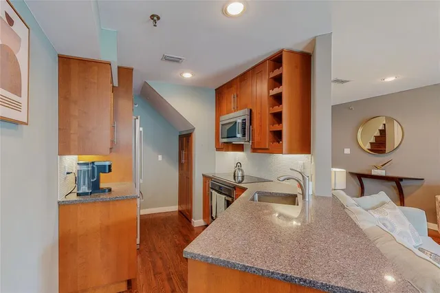 a kitchen with stainless steel appliances granite countertop a sink and a refrigerator