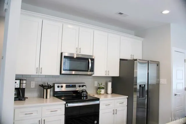 a kitchen with a refrigerator stove and white cabinets