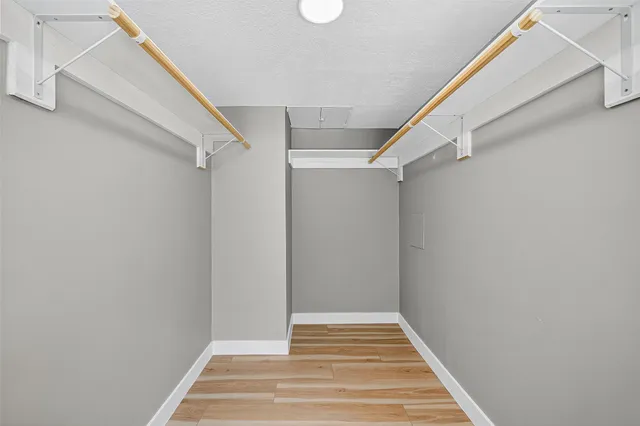 an empty room with wooden floor cabinet and windows