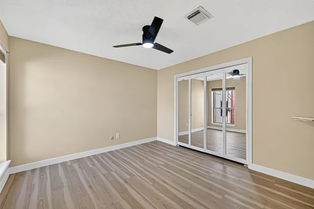 a view of a room with wooden floor and a ceiling fan