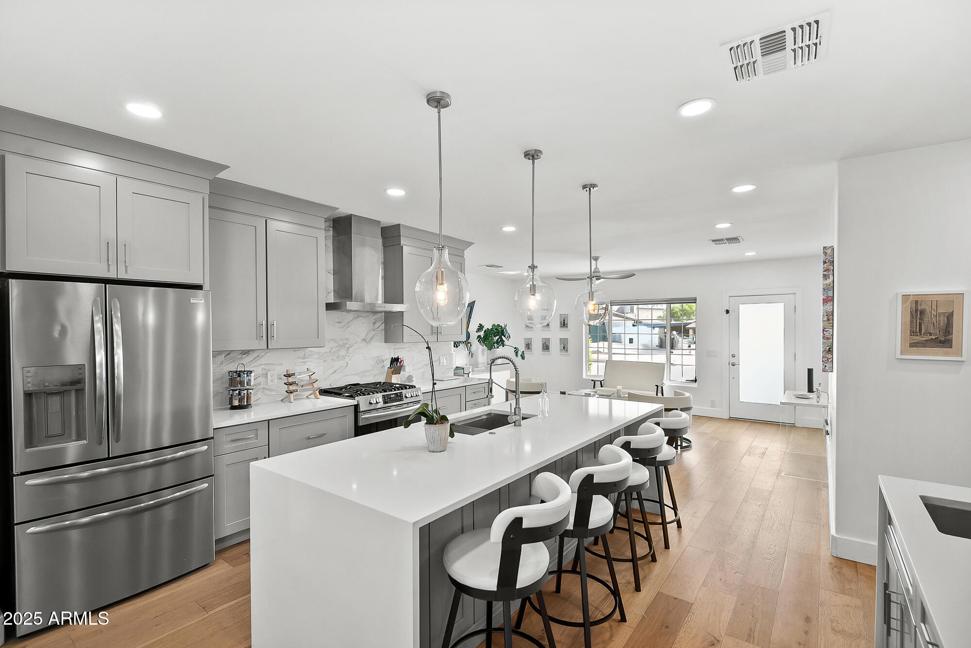 4526 East Heatherbrae Drive Phoenix, AZ 85018 - Photo 18 of 34 a kitchen with stainless steel appliances kitchen island granite countertop a sink a stove a refrigerator and island with wooden floor