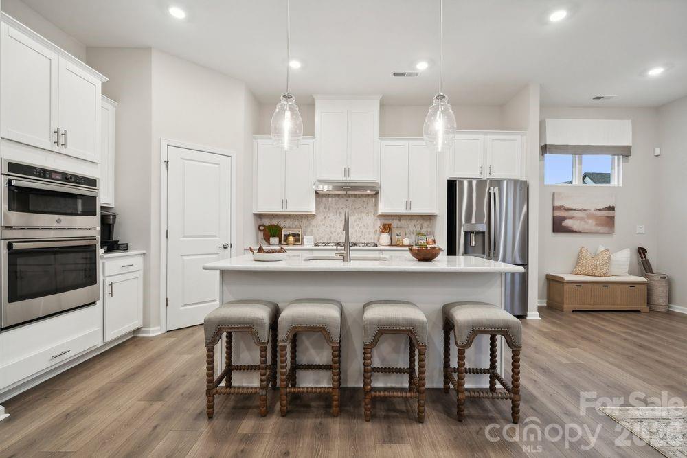 8671 Miles Gap Road Indian Land, SC 29707 - Photo 12 of 31 a large kitchen with stainless steel appliances granite countertop a white table chairs and a refrigerator
