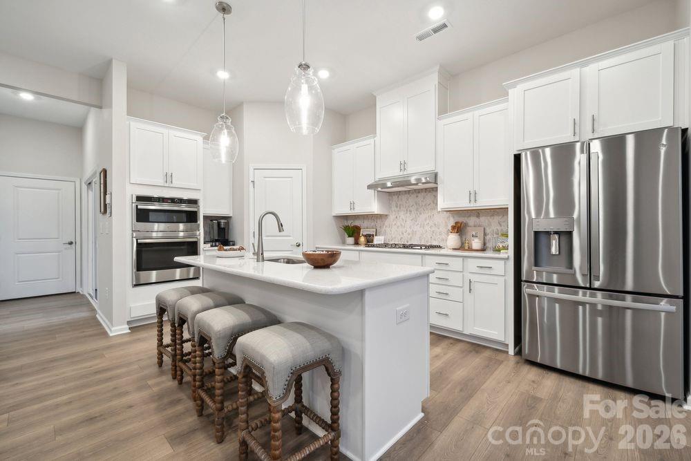 8671 Miles Gap Road Indian Land, SC 29707 - Photo 13 of 31 a kitchen with stainless steel appliances granite countertop a refrigerator a sink dishwasher a stove and white cabinets with wooden floor