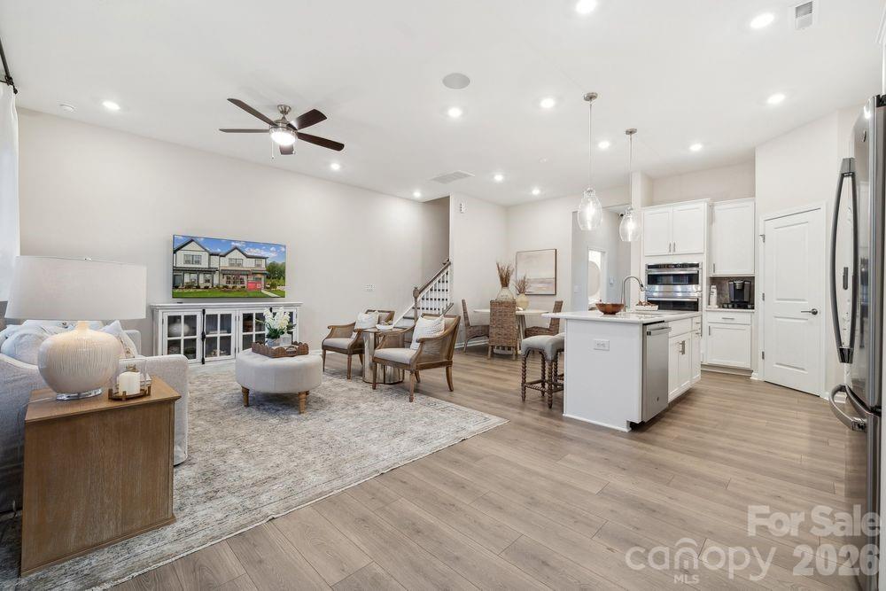 8671 Miles Gap Road Indian Land, SC 29707 - Photo 7 of 31 a large living room with stainless steel appliances kitchen island granite countertop a stove a sink a refrigerator and white cabinets with wooden floor