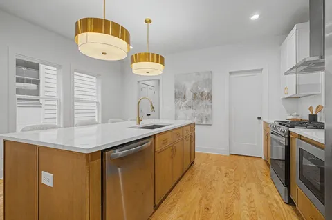 a kitchen with stainless steel appliances granite countertop a sink a stove oven a counter space and cabinets