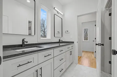 a bathroom with a granite countertop double vanity sink and mirror