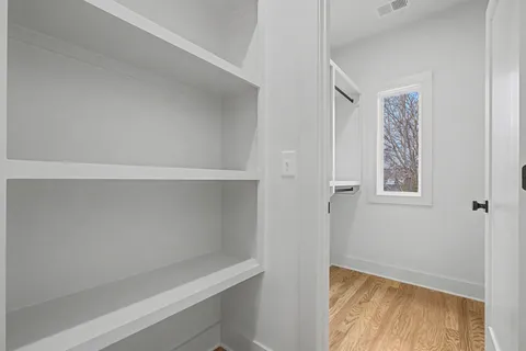 a view of an empty room with closet and wooden floor