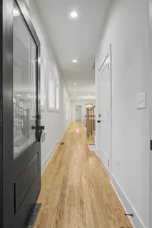 a view of a hallway with wooden floor and a bathroom