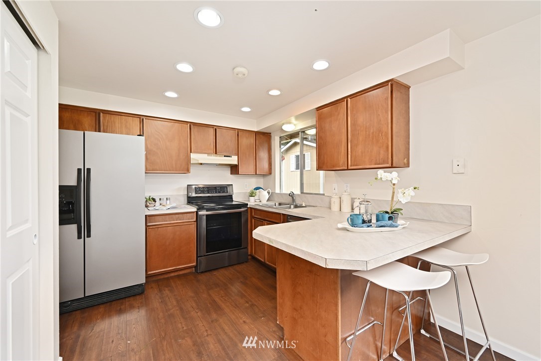 9211 3rd Place Southeast Everett, WA 98208 - Photo 11 of 33 a kitchen with stainless steel appliances granite countertop a refrigerator a sink a stove a microwave and island with wooden floor