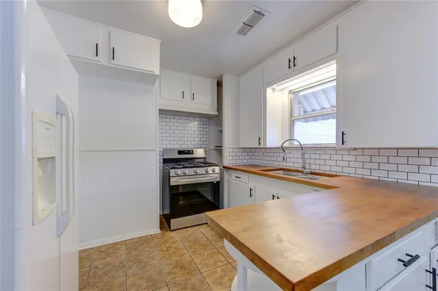a kitchen with granite countertop a sink stainless steel appliances and white cabinets