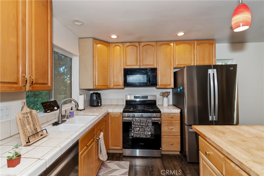 198 Pine Ridge Road Crestline, CA 92325 - Photo 32 of 45 a kitchen with a sink a microwave a refrigerator and wooden cabinets