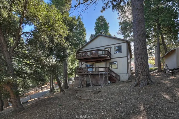 a view of a wooden house with a yard and large trees