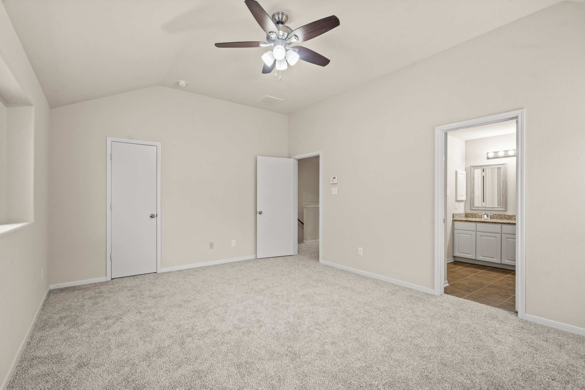 3118 Winchester Rnch Trail Katy, TX 77493 - Photo 14 of 22 This angle of the primary bedroom highlights the direct access to both the en-suite bath and two separate closets — a thoughtful layout that offers exceptional storage and privacy. Vaulted ceilings, soft carpet, and neutral tones complete this warm and welcoming space.